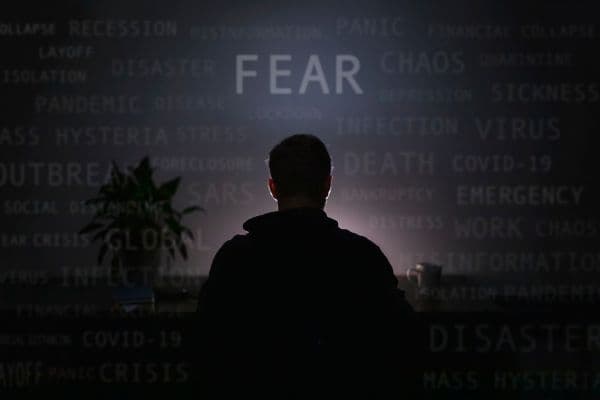 Silhouette eines Mannes vor einer Wand mit Wörtern wie Fear, Chaos, Crisis und Panic