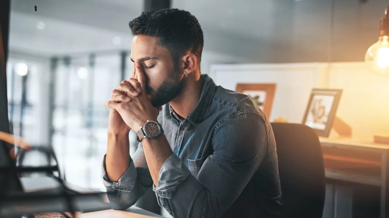 Man in office sitting thoughtfully at laptop – focus, stress management and mental clarity in everyday work